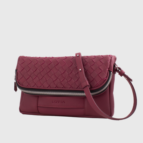 Lovia Aira burgundinvärinen nahkainen crossbody-laukku, jossa punottu läppä ja hopeanvärinen vetoketju. | Lovia Aira burgundy leather crossbody bag with woven flap and silver zipper.